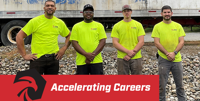 Four JGM employees standing together in yellow Hi-Vis shirts with JGM logo and text overlay Accelerating Careers